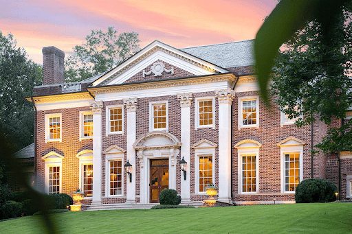 Stately brick estate home exterior illuminated at dusk