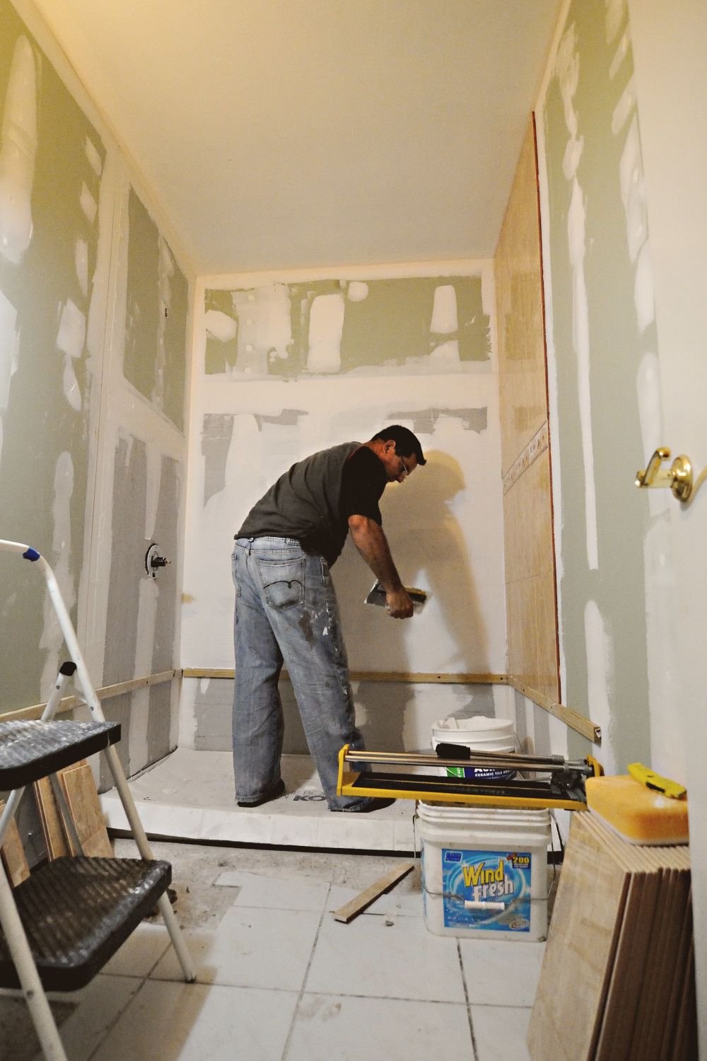 Worker installing drywall during a bathroom renovation