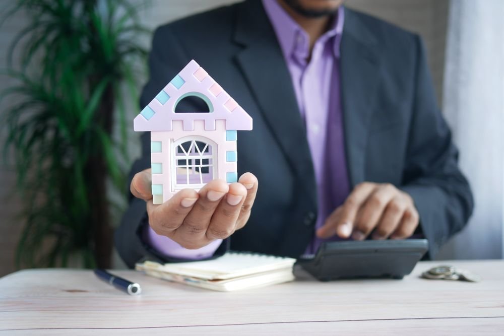 Person holding a model house while comparing renovation and moving costs